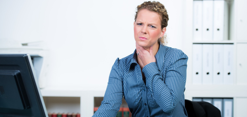 Frau in einem Büro fasst sich an den schmerzenden Hals