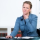 Frau im Büro greift sich wegen Halsschmerzen an den Hals